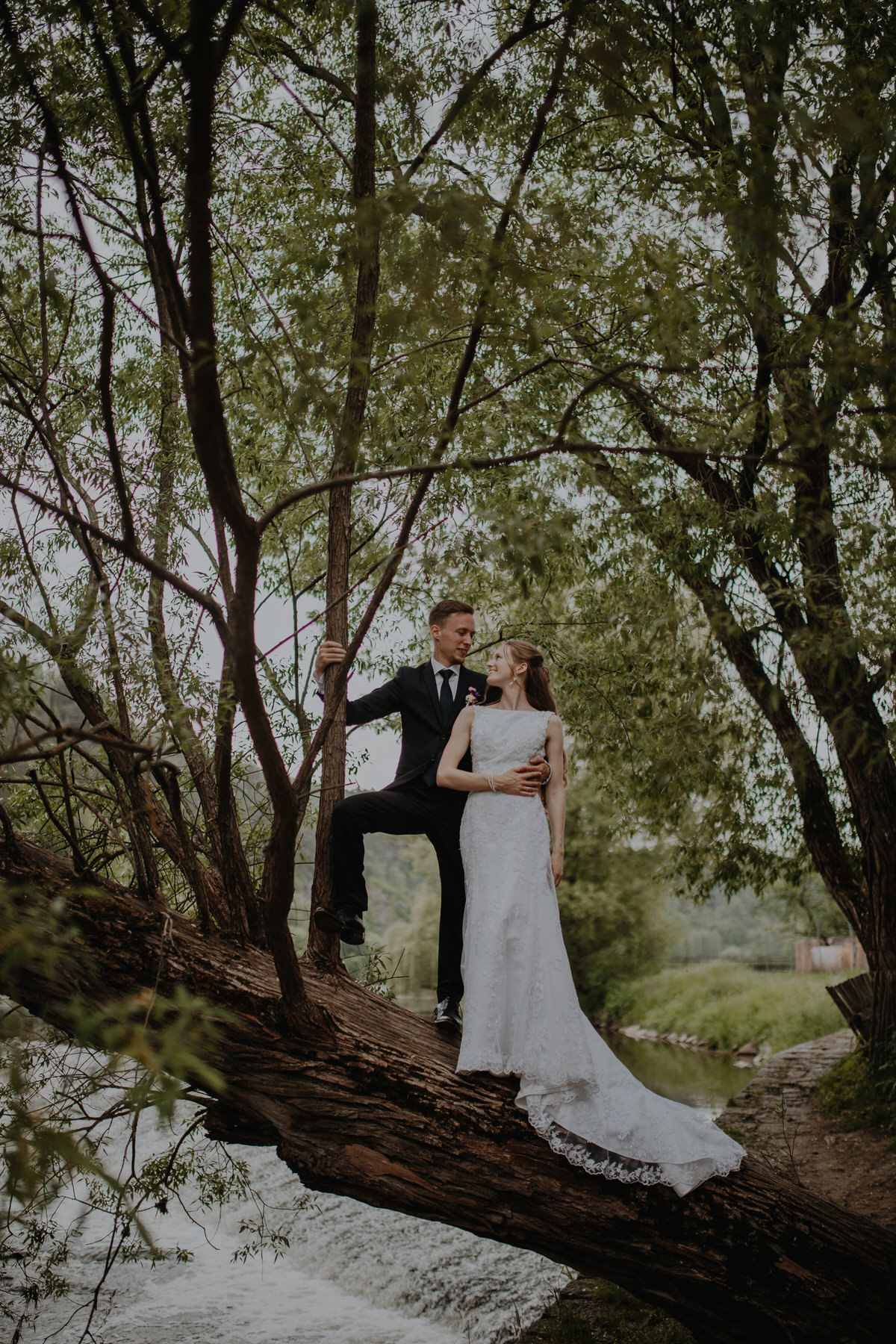 102_resort-chobot-wedding-photographer-monika-chano The newlyweds stand on a tree over the water.