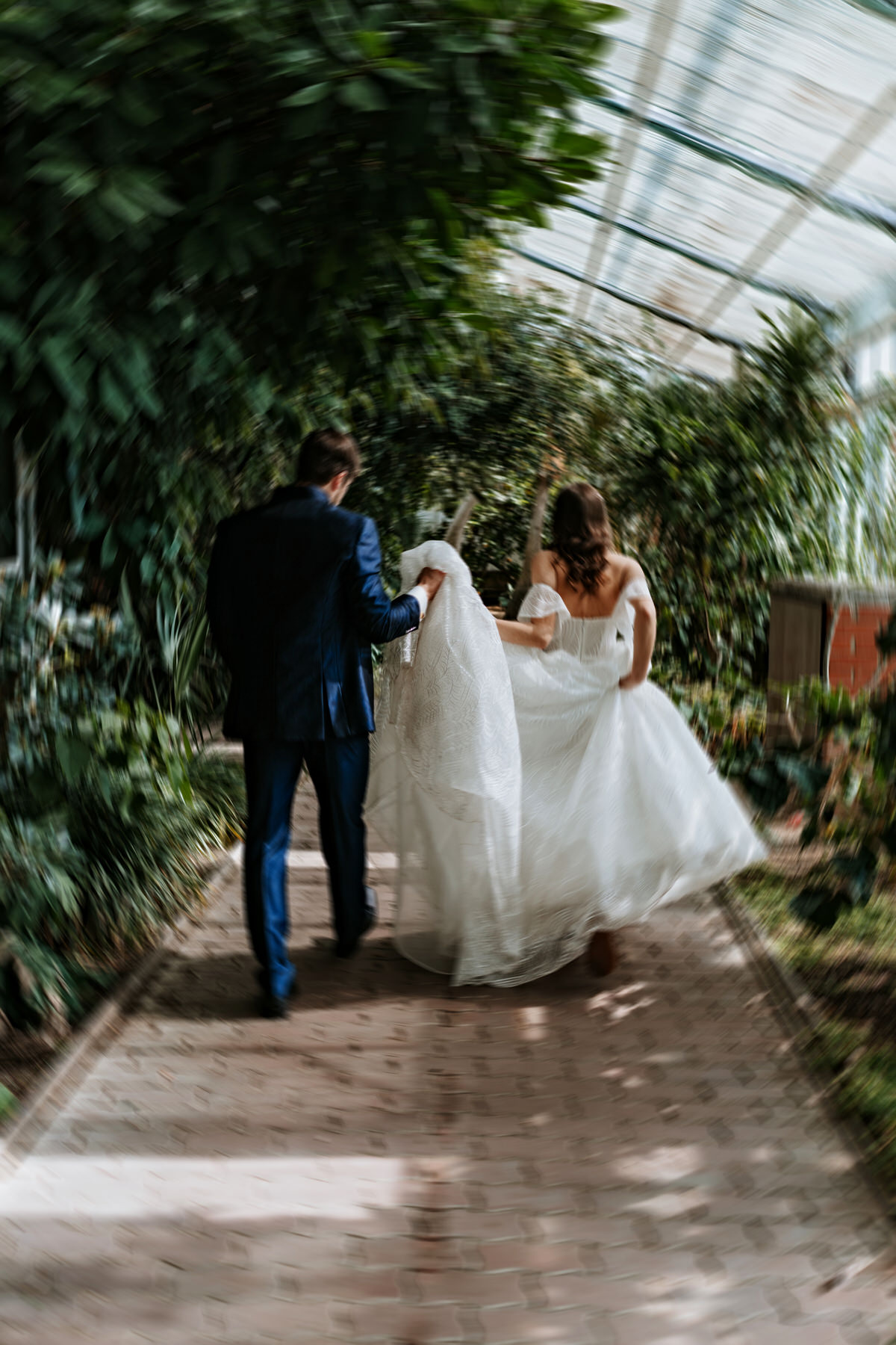 Newlyweds walk through the Flora Olomouc greenhouse.