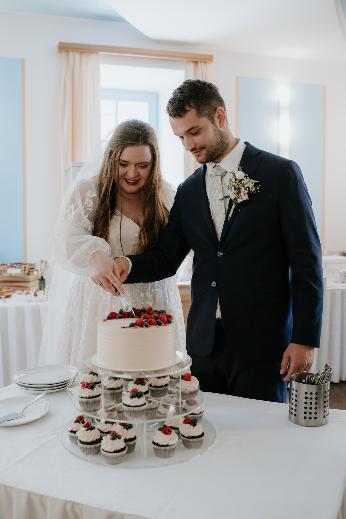 The newlyweds are cutting their wedding cake.