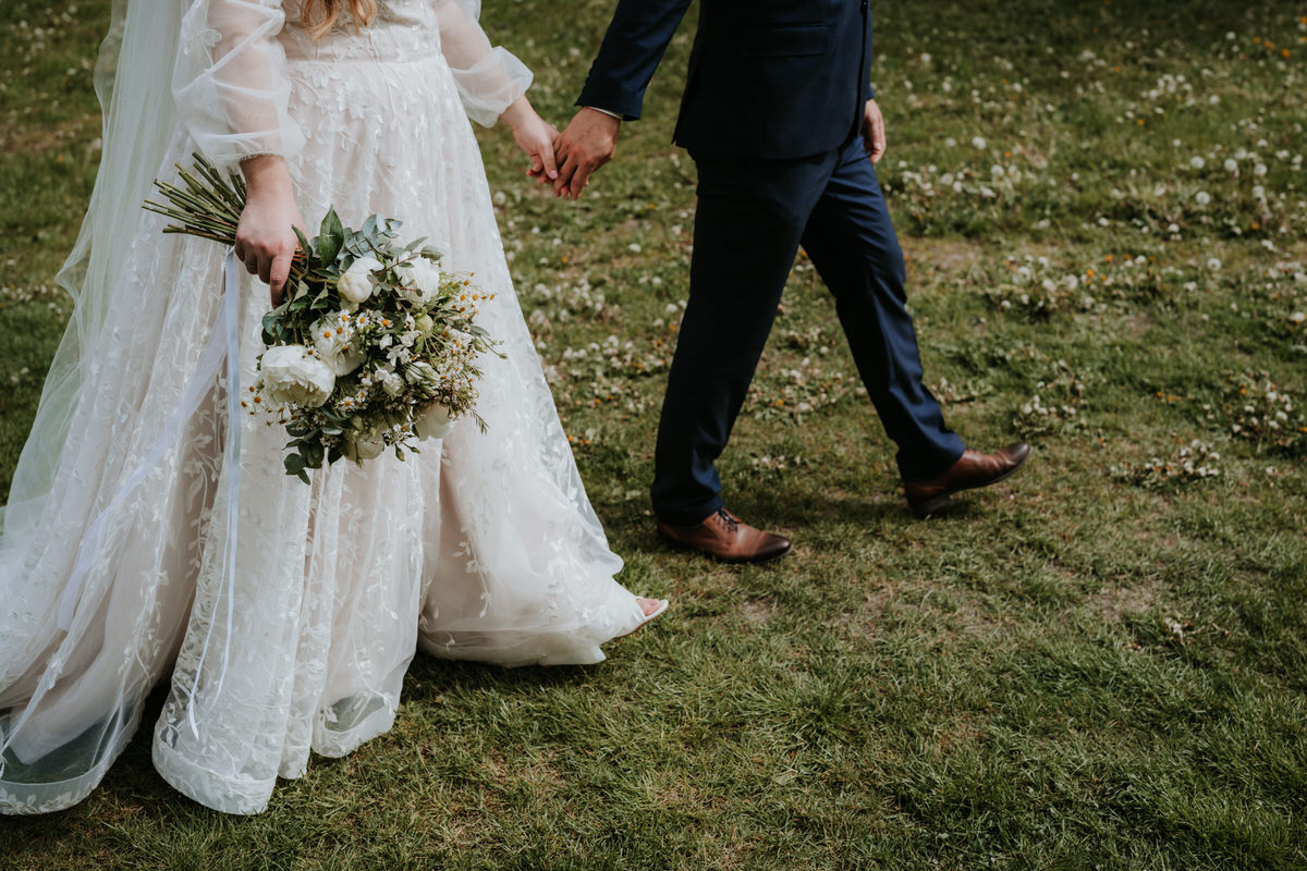 Newlyweds walk hand in hand during a wedding photo shoot.Newlyweds walk hand in hand during a wedding photo shoot.
