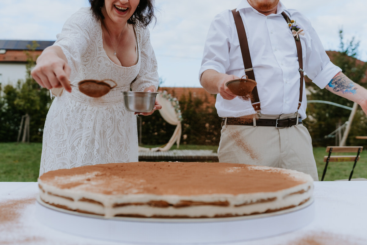 The newlyweds decorate their huge tiramisu wedding cake.
