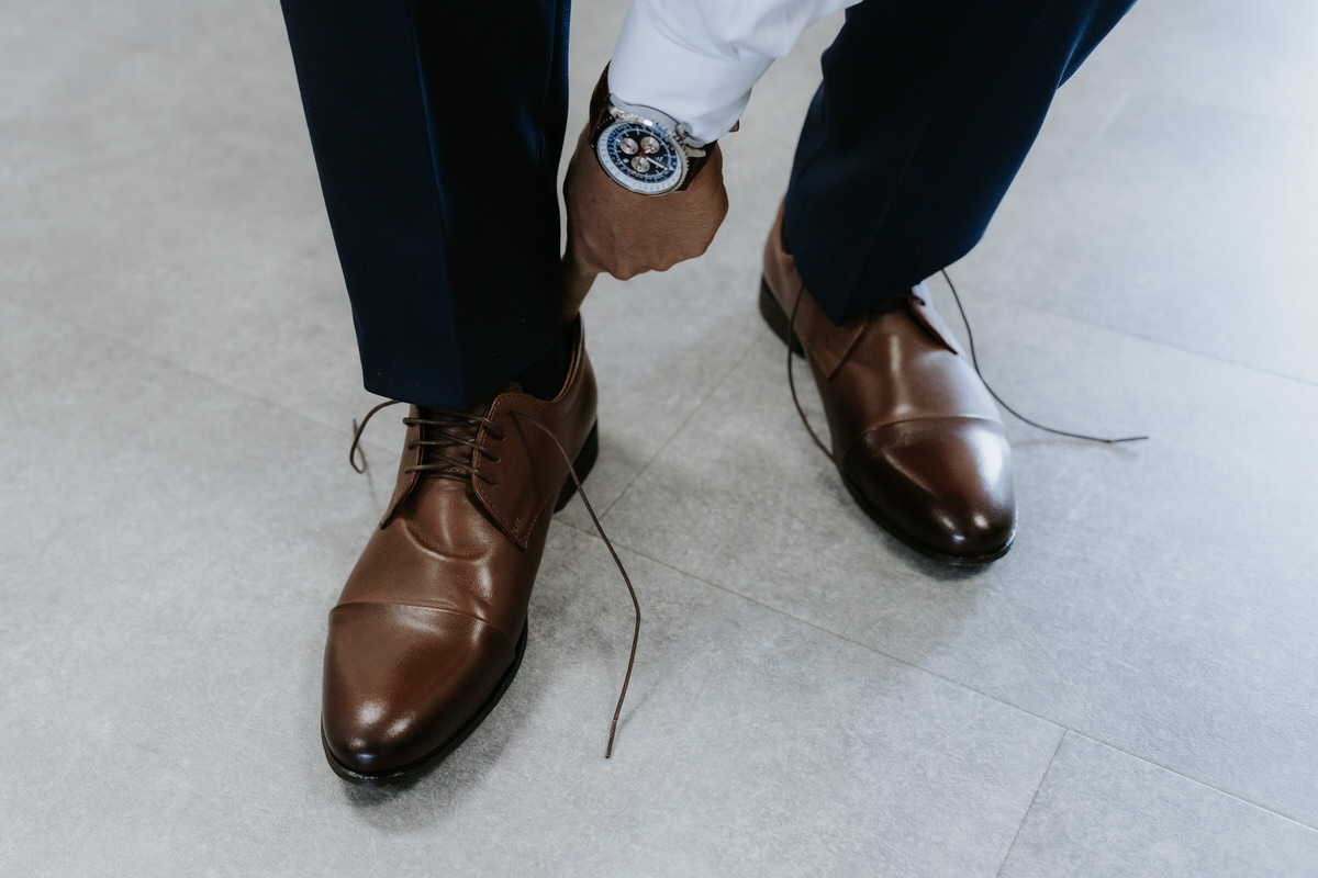 The groom is tying his wedding shoes.