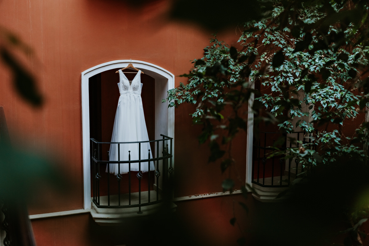 Detail of a wedding dress hanging on a balcony.
